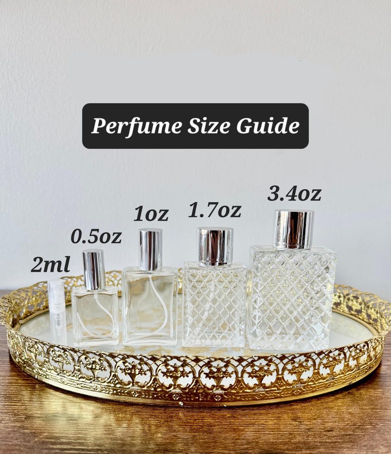 May include: A perfume size guide featuring various clear glass perfume bottles with silver sprayers. The bottles range in size from 2ml to 3.4oz, displayed on a gold-colored decorative tray. The text "Perfume Size Guide" is at the top.