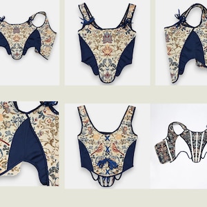 Op de afbeelding: Een verzameling cr&egrave;mekleurige korsetten met een bloemen- en vogelpatroon, geaccentueerd met marineblauwe panelen en afwerking. De korsetten hebben verschillende bandjes en strikdetails, wat een vintage esthetiek laat zien.