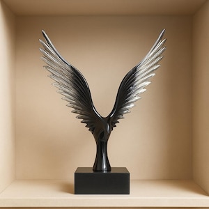 May include: A black sculpture of a bird with outstretched wings, mounted on a black rectangular base. The wings have a detailed, layered design, and the sculpture has a glossy finish. The artwork is displayed in a neutral-toned alcove.