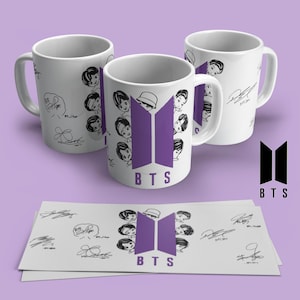May include: Three white ceramic mugs with black and purple graphics. The mugs feature cartoon illustrations of faces, signatures, and the letters "BTS". A matching design is printed on a stack of paper. The background is a light purple.