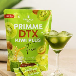 May include: A green package of Primme DTX Kiwi Plus Fiber dietary supplement with kiwi fruit illustrations. A green drink with ice cubes in a martini glass is next to the package. Two small packets are in front of the package.