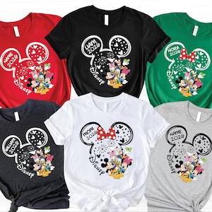 a collection of six t-shirts, each featuring a unique design with Disney characters and text. The t-shirts are arranged in a grid pattern, showcasing various colors and styles.