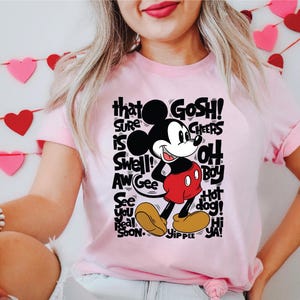 a woman wearing a pink shirt with a mickey mouse on it
