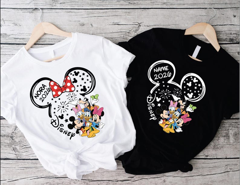 two t-shirts hanging on wooden hangers, each featuring a Disney character design.