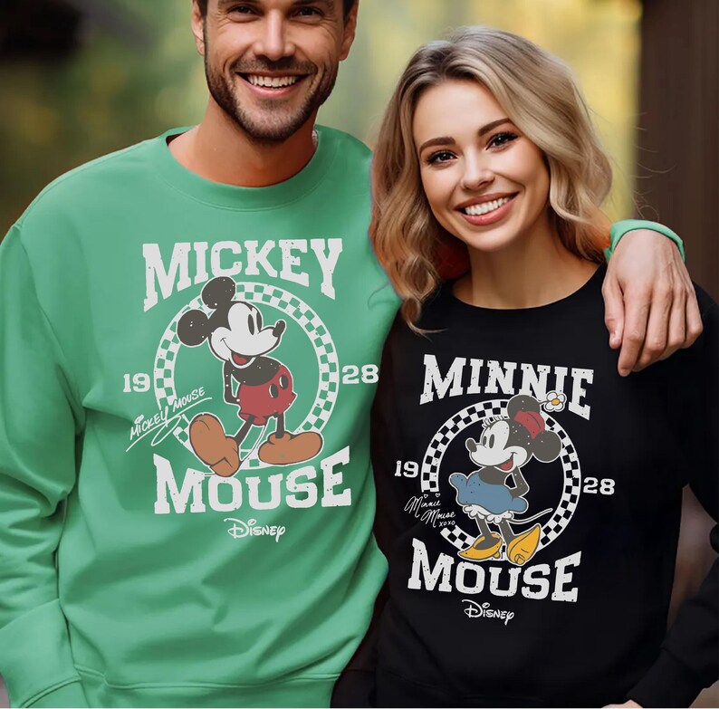 A man and a woman are standing together, both wearing Mickey Mouse sweatshirts.