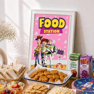May include: A framed sign with a pink background and white clouds featuring Toy Story characters Woody, Jessie, Buzz Lightyear, and Forky with the text FOOD STATION, displayed alongside a basket of sandwiches, chicken nuggets, crackers, popcorn, fruit, and juice.