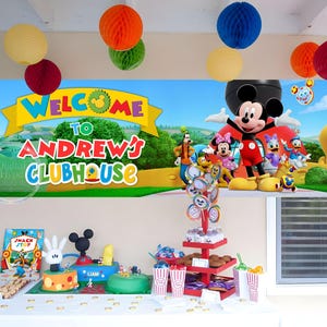 Peut inclure: Une bannière de fête rectangulaire présentant un paysage coloré avec Mickey, Minnie, Dingo, Donald et Daisy. Le texte indique Welcome to Andrew's Clubhouse en grandes lettres multicolores et grasses sur une bannière en forme de ruban jaune.