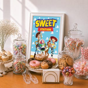 Op de afbeelding: Een ingelijst bord met de tekst SWEET STATION en Toy Story-figuren, omringd door glazen potten gevuld met kleurrijke snoepjes, lolly's en koekjes, met een bord met geglazuurde donuts en een gouden servettenhouder op een tafel.