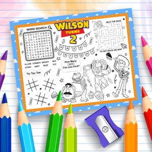 Può includere: Un foglio di attività di compleanno con la scritta "Wilson Turns 2" e vari giochi, tra cui un cruciverba, un labirinto e il tris. Il foglio presenta personaggi dei cartoni animati ed è circondato da matite colorate.
