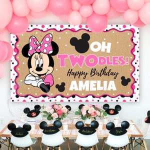 May include: A rectangular party backdrop featuring a tan background with a pink and black polka dot border. It displays a Minnie Mouse illustration, the text OH TWODLES! Happy Birthday AMELIA, and black Mickey Mouse head silhouettes.