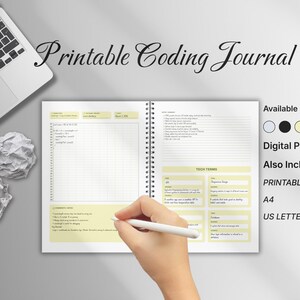 May include: A coding journal with a spiral binding, open to a page with a grid layout and tech terms. The journal is labelled "Printable Coding Journal" and includes digital papers, printable formats, and colour choices. A laptop and crumpled paper are also visible.