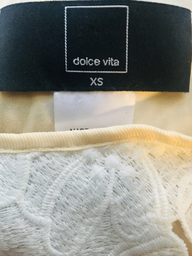 May include: A white lace top with a black tag that says "dolce vita" and "XS".