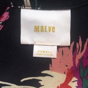 Może przedstawiać: Czarno-biała bluzka z kwiatowym nadrukiem z białą metką z napisem "Maeve" i "XSmall Made in China."