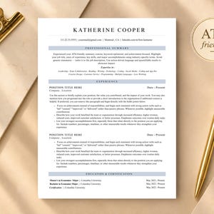 Puede incluir: Una plantilla de currículum profesional titulada Katherine Cooper con secciones para resumen profesional, experiencia y educación. El documento presenta un diseño limpio con texto negro sobre fondo blanco e incluye un bolígrafo y un clip dorados.
