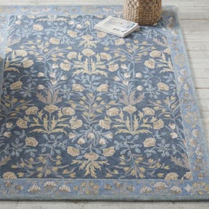 a blue and gold floral patterned rug with a woven basket placed on top of it.