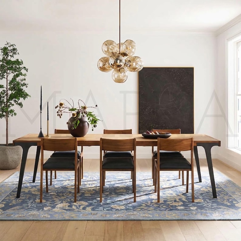 a modern dining room with a wooden table and chairs, a large chandelier, a plant, and a blackboard on the wall.
