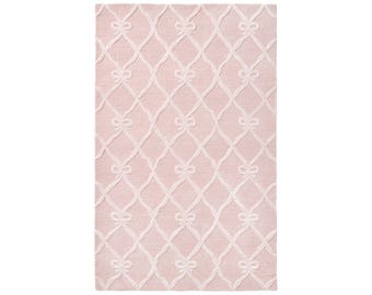 May include: A rectangular area rug in a soft pastel pink hue featuring a repeating white lattice pattern. Each intersection of the lattice is accented with a small, stylised bow detail, creating a consistent grid across the entire surface.
