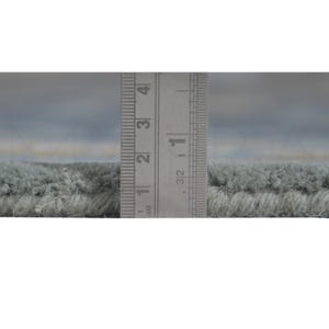A ruler is being used to measure the width of a carpet or rug, with the ruler placed between the two ends of the rug.