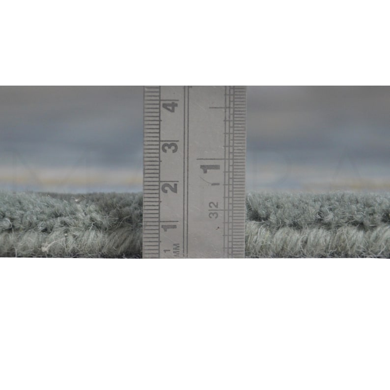 A ruler is being used to measure the width of a carpet or rug, with the ruler placed between the two ends of the rug.