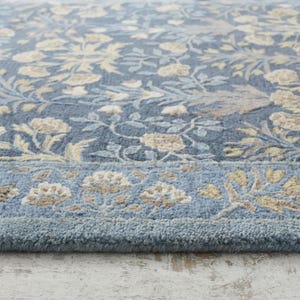 a close-up view of a blue and white floral patterned rug on a wooden floor.