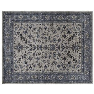 May include: A rectangular area rug featuring a light gray center field adorned with a symmetrical floral vine pattern in shades of dark blue, charcoal, and slate. The rug is framed by a wide, intricate border with repeating floral motifs.