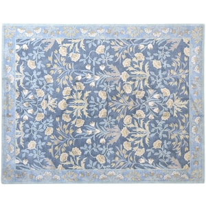 a large, square rug with a floral pattern in shades of blue and yellow. The rug has a decorative border around the edges, adding to its overall aesthetic appeal.
