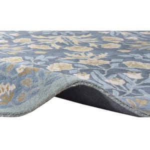 a close-up view of a blue and yellow floral patterned rug or carpet, with a dark gray or black backing.