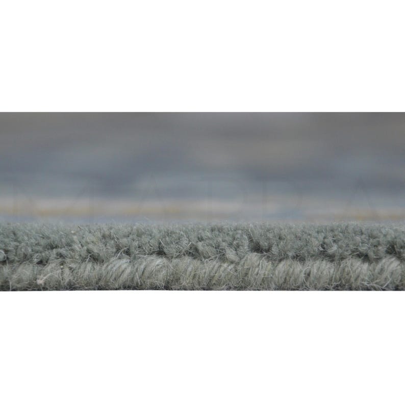 a close-up view of a textured gray carpet or rug, with a blurred background that appears to be a cloudy sky.
