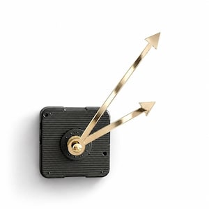 May include: A black square clock movement mechanism featuring a ribbed texture on its front surface. Attached to the center is a pair of metallic gold clock hands, each ending in a pointed arrow shape, positioned at an upward angle.