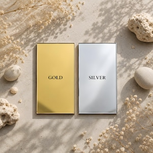 May include: Two rectangular metal plates with a smooth, reflective finish. The left plate is gold-colored with the word GOLD printed in black, and the right plate is silver-colored with the word SILVER printed in black, both featuring thin borders.