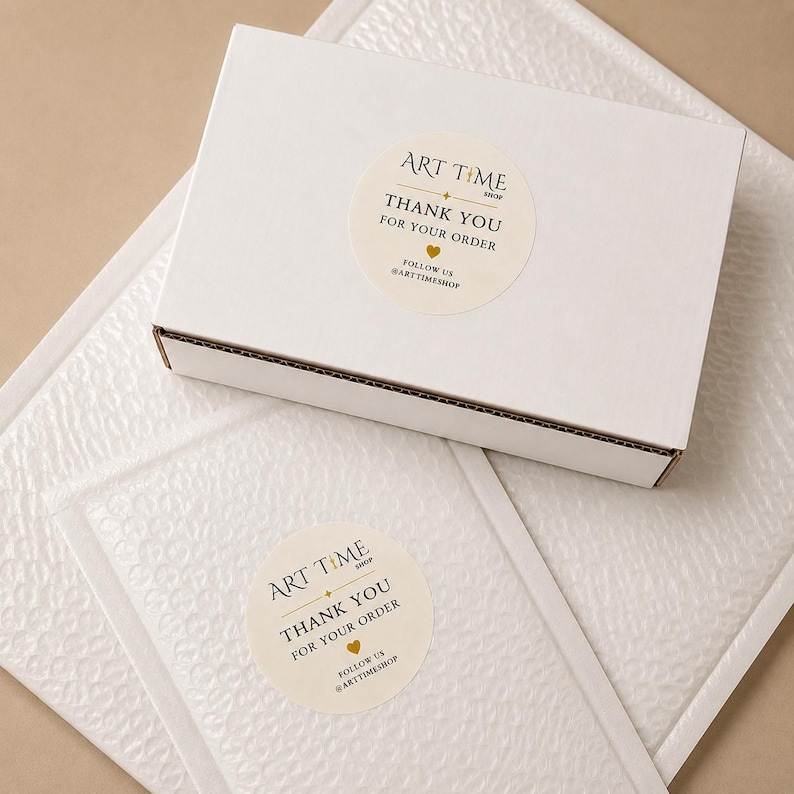 May include: A white rectangular cardboard shipping box and a white bubble mailer, each featuring a round cream-colored sticker. The stickers display the text ART TIME SHOP, THANK YOU FOR YOUR ORDER, a small gold heart, and FOLLOW US @ARTTIMESHOP.