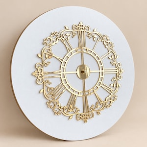 May include: A circular wall clock featuring a white face and a gold-colored metal overlay. The overlay displays Roman numerals and intricate scrollwork patterns with leaf motifs. The center of the clock has a simple gold-colored circular hub.