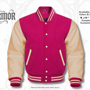Op de afbeelding: Een roze wollen varsity-jack met crèmekleurige leren mouwen, een drukknoopsluiting aan de voorzijde en gestreepte geribbelde boorden bij de mouwen en kraag. De tekst NURMOR staat links, met Available in All Colors & Sizes en Completely Customizable rechts.