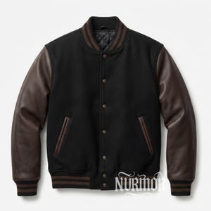 Puede incluir: Una chaqueta universitaria negra con mangas de cuero marrón oscuro, cuerpo de mezcla de lana negra y cierre frontal de botones a presión. El cuello, los puños y el dobladillo están acanalados con rayas marrones. Incluye el texto NURMOR.