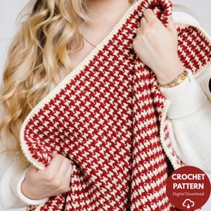 May include: A red and cream houndstooth pattern crochet blanket. The blanket is folded, showing the pattern and cream-coloured border. The image includes a round graphic with the words "CROCHET PATTERN" and "Digital Download".