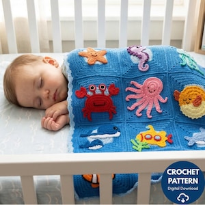 Pode incluir: Um cobertor de bebê de crochê azul com aplicações de criaturas marinhas, incluindo uma estrela do mar, caranguejo, polvo e cavalo-marinho. O cobertor tem um padrão quadrado e uma borda branca. Um bebê está sob o cobertor.