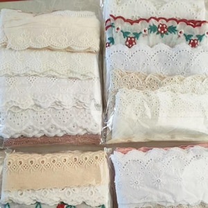 Może przedstawiać: Zestaw białych, kremowych i czerwonych koronowych lamówek z różnymi wzorami, w tym falbankami, wzorami oczek i haftowanymi wiśniami.