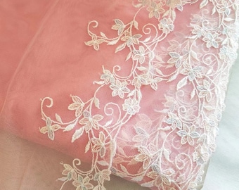 May include: White lace trim with a floral design. The lace is delicate and features a light pink background.