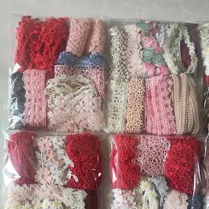 Könnte beinhalten: Sortiment an Spitzenborten in verschiedenen Farben und Mustern, darunter Rot, Rosa, Weiß und Beige. Die Spitzenborten sind in durchsichtigen Plastiktüten verpackt.