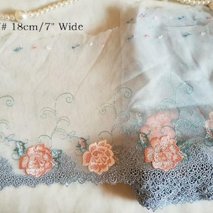 May include: Delicate floral lace trim, 7 inches wide, featuring embroidered peach-colored roses and teal accents. The lace has a scalloped edge and is set against a sheer, light blue fabric. Text reads "407# 18cm/7" Wide".
