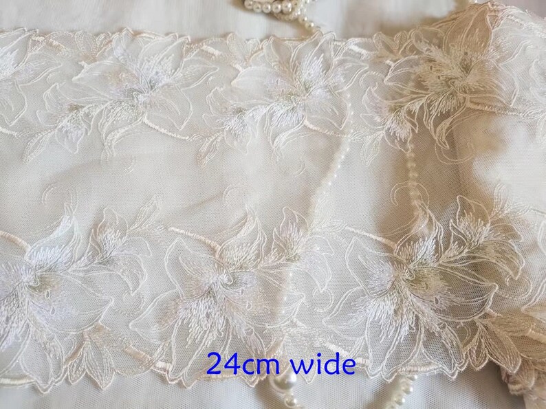 May include: White floral lace trim with a delicate design. The trim is 24 inches wide.