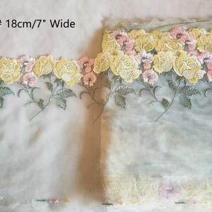 Op de afbeelding: Een close-up van gele en roze bloemen geborduurd op een transparante stof. De bies is 18 cm/7 inch breed. 161#