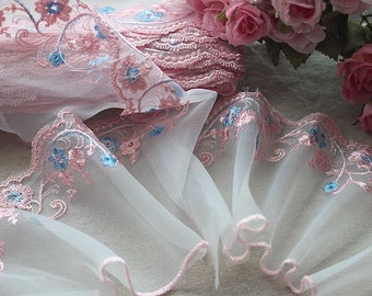 Peut inclure: Dentelle à fleurs rose et bleue brodée avec un bord festonné. La dentelle est délicate et transparente, et elle serait parfaite pour ajouter une touche d'élégance à tout projet.