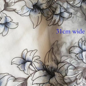 May include: White sheer fabric with embroidered blue and brown lilies. The fabric is 31 inches wide.