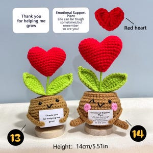 Pu&ograve; includere: Due piante all'uncinetto fatte a mano con fiori rossi a forma di cuore e foglie verdi. I vasi marroni hanno facce sorridenti e contengono piccole carte con testo. L'altezza delle piante &egrave; di 14 cm.