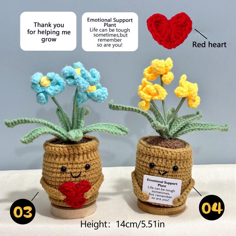 Pu&ograve; includere: Due piante in vaso all'uncinetto con facce sorridenti, una con fiori blu e un cuore rosso, l'altra con fiori gialli e un cartello con scritto "Emotional Support Plant". Altezza: 14 cm.