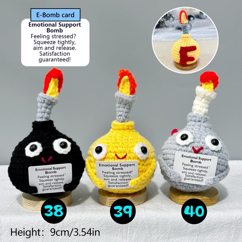 May include: Three handmade crochet "Emotional Support Bombs" in black, yellow, and gray, each with a red and yellow flame. Each bomb has a smiling face and a tag with text. Height: 3.54 inches.