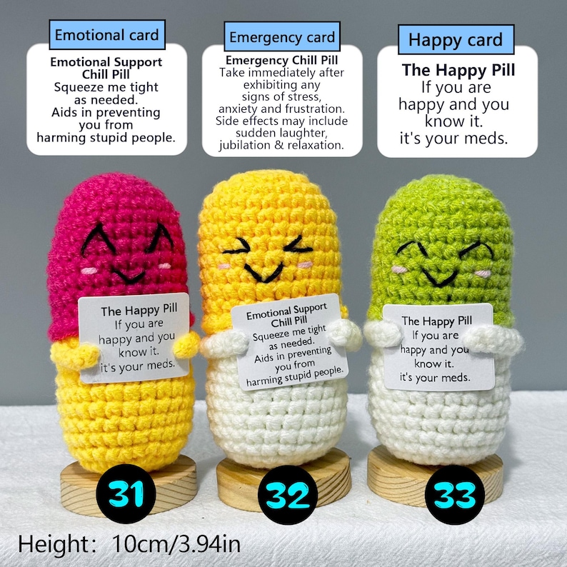 May include: Three handmade crochet pill-shaped toys in pink, yellow, and green, each with a smiling face and a small card. The cards have different messages. The height of each toy is 3.94 inches. Each toy is on a small wooden base.