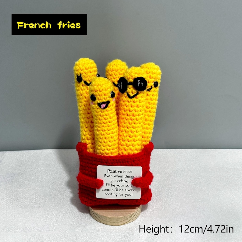 May include: Crocheted yellow French fries with smiling faces and sunglasses, in a red container. The container has a label that reads "Positive Fries". The height is 4.72 inches.