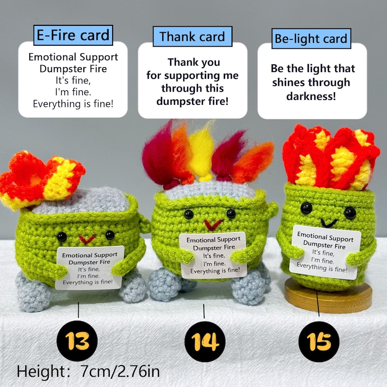 May include: Three crocheted figures, each with a green body, gray top, and a different colored flame. Each figure holds a card with text: "Emotional Support Dumpster Fire." Height is 2.76 inches.